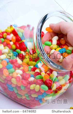 crop of clear open jar and handful of colorful jelly beans