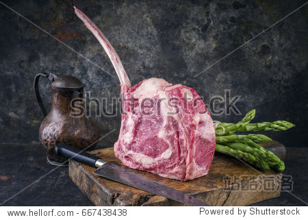 raw dry aged wagyu tomahawk steak with green asparagus as close