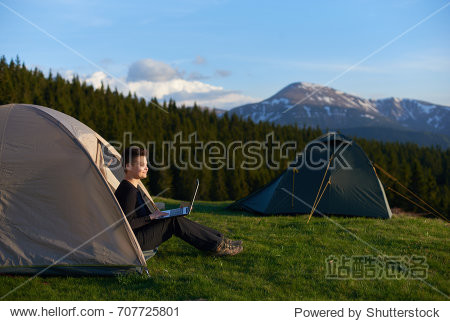 mountains sitting in her tent working on the laptop copyspace