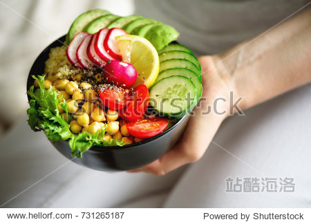 girl holds in hands vegan, detox raw buddha bowl with avocado