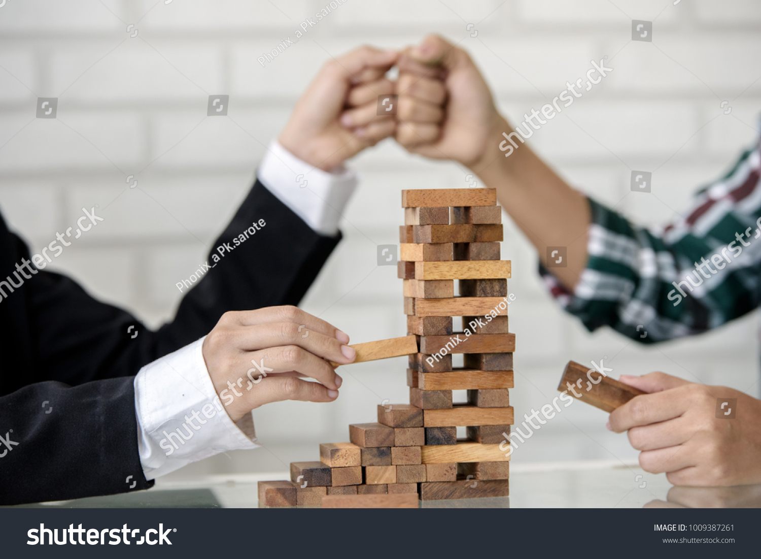 Teamwork and cooperation concept -  young business hands building a structure of wooden blocks . teamwork business signs on rustic table surface. 