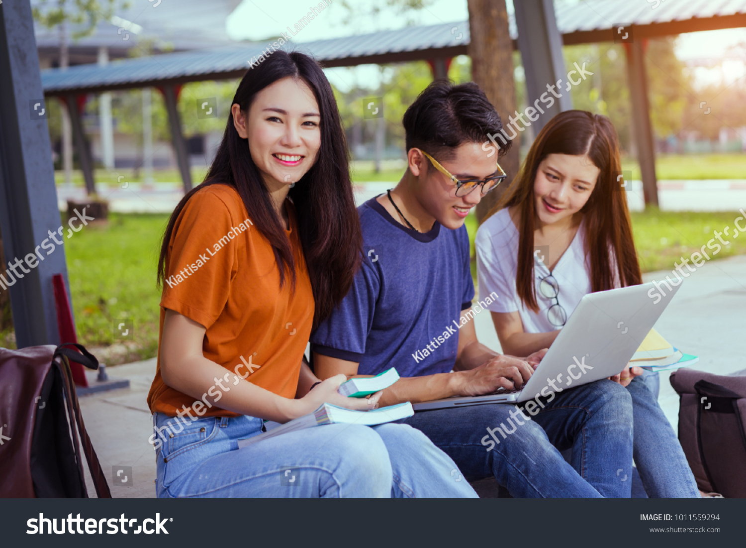 Students young asian together reading book study smiling with tablet laptop computer at university high school campus college in summer holiday relaxation