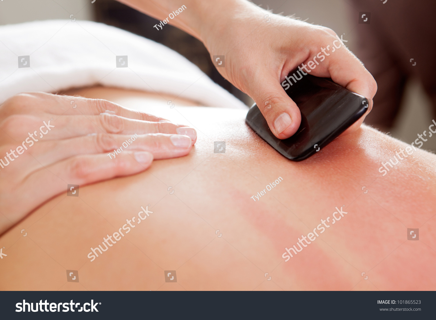 Large bone scraper tool being used ruing a guasha acupuncture treatment