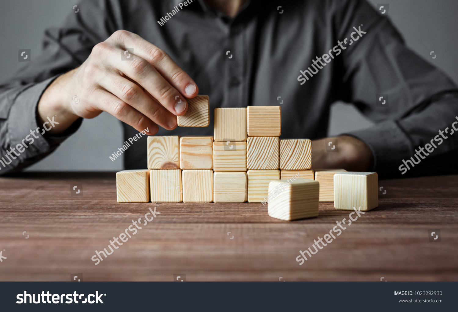 Closeup of businessman making a pyramid with empty wooden cubes. Concept of business hierarchy and business strategy.