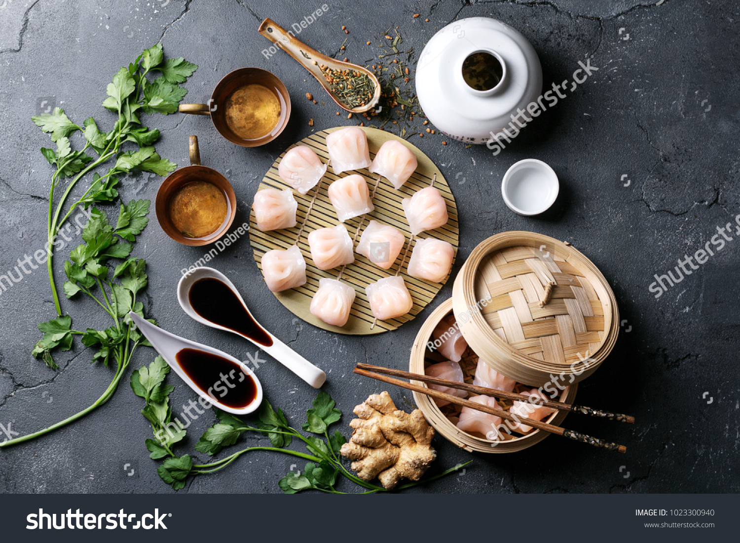 Home made chinese and korean dumplings served on the traditional steamer and bamboo mat decorated with soy sauce parsley giner and green tea. Top View