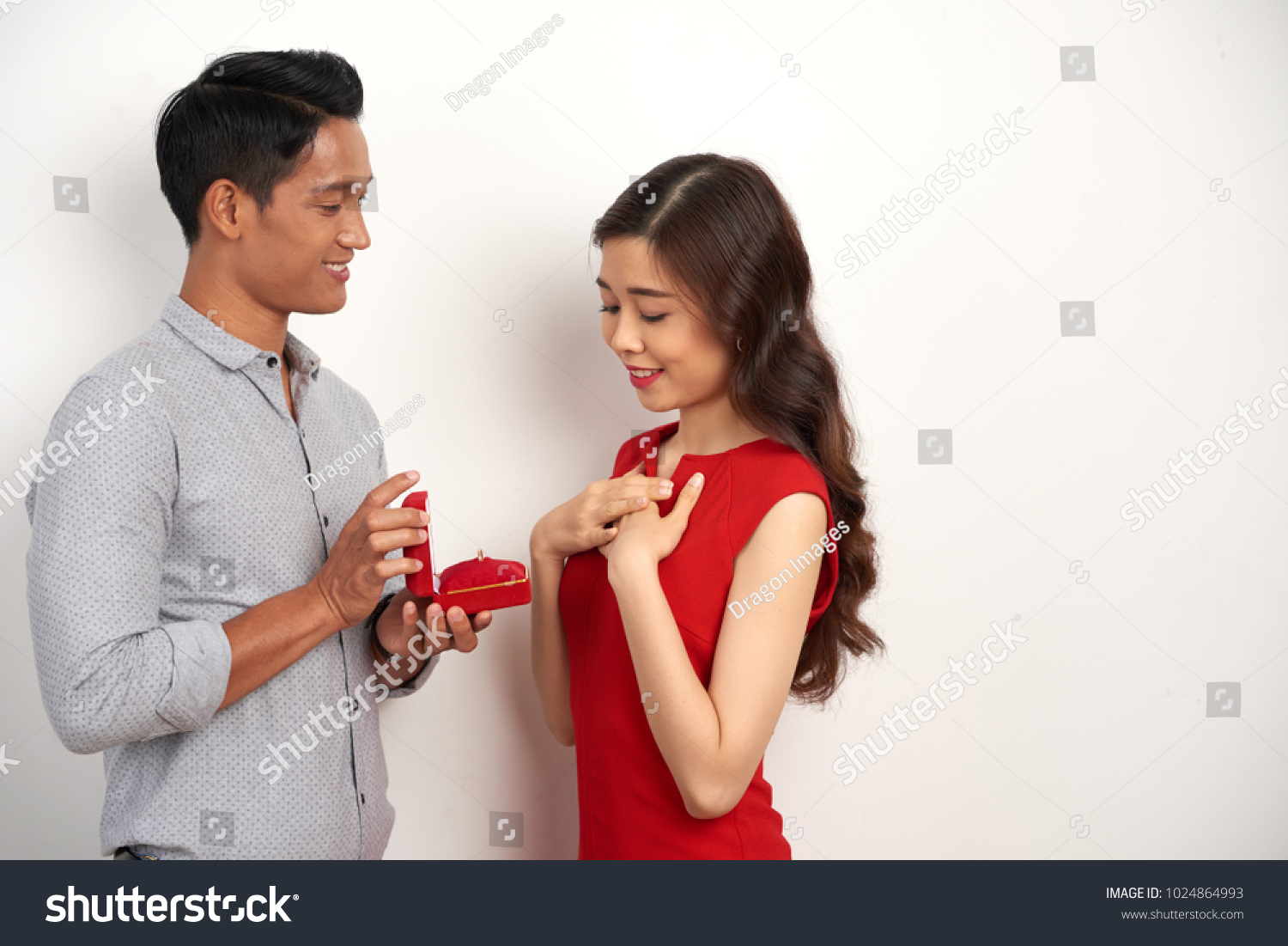 Young man proposing to his beautiful girlfriend and giving her engagement ring
