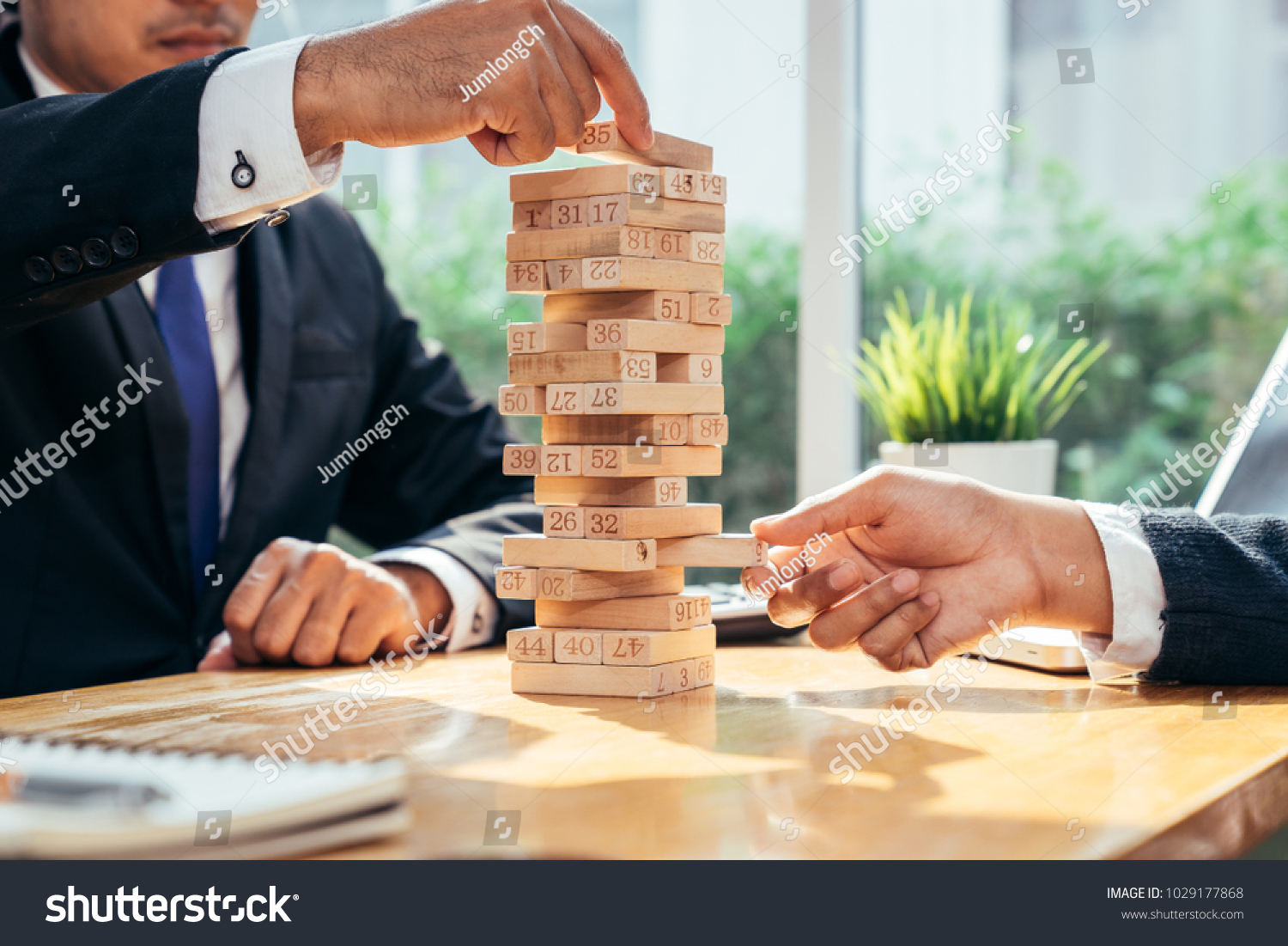 An asian businessman arraging the small wooden blocks on his working desk by close-up  Business construction and fail concept.