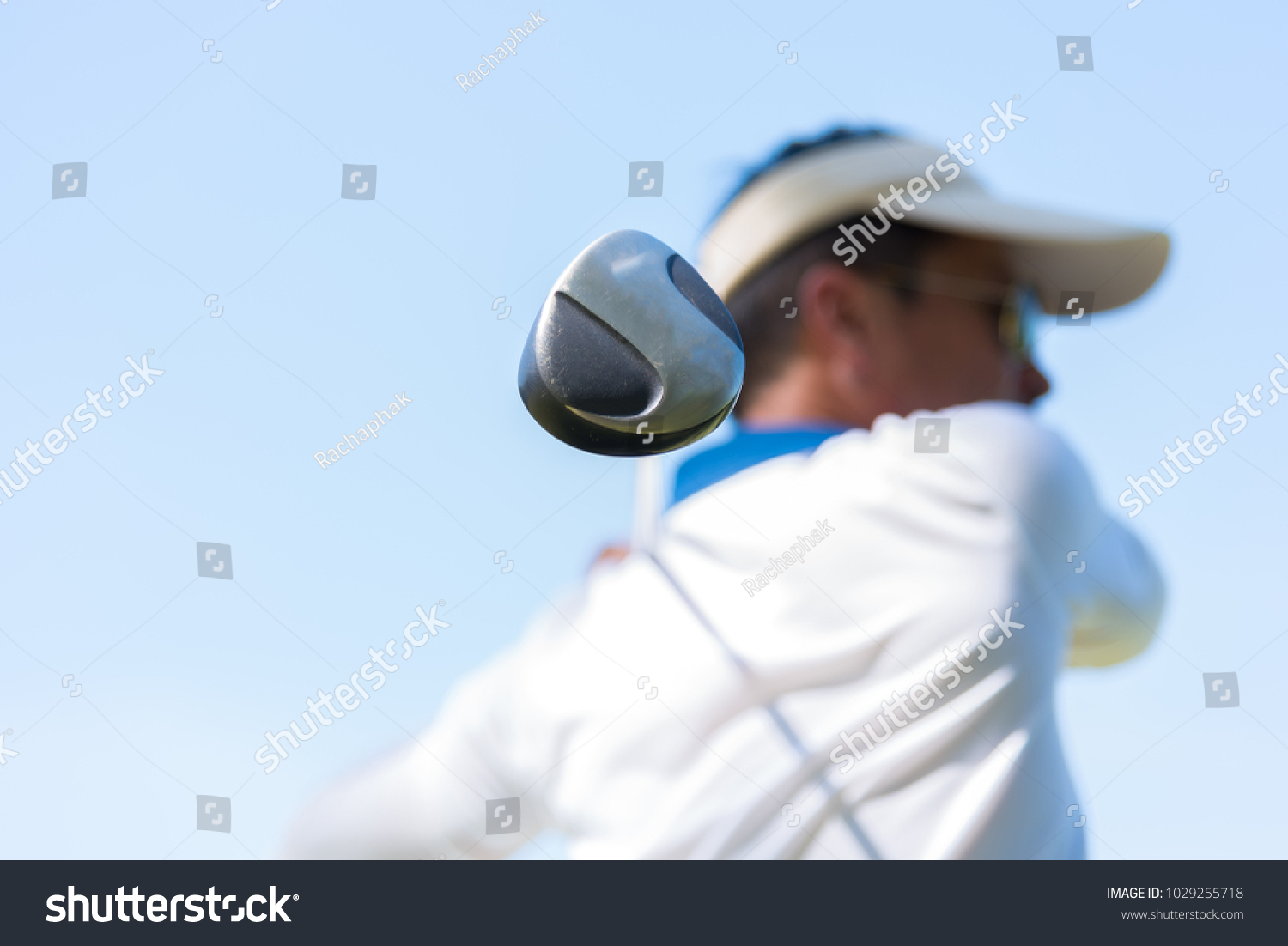 Asian golfer hitting golf shot with club on course while on summer vacation. Selected focus on player hand holding golf.