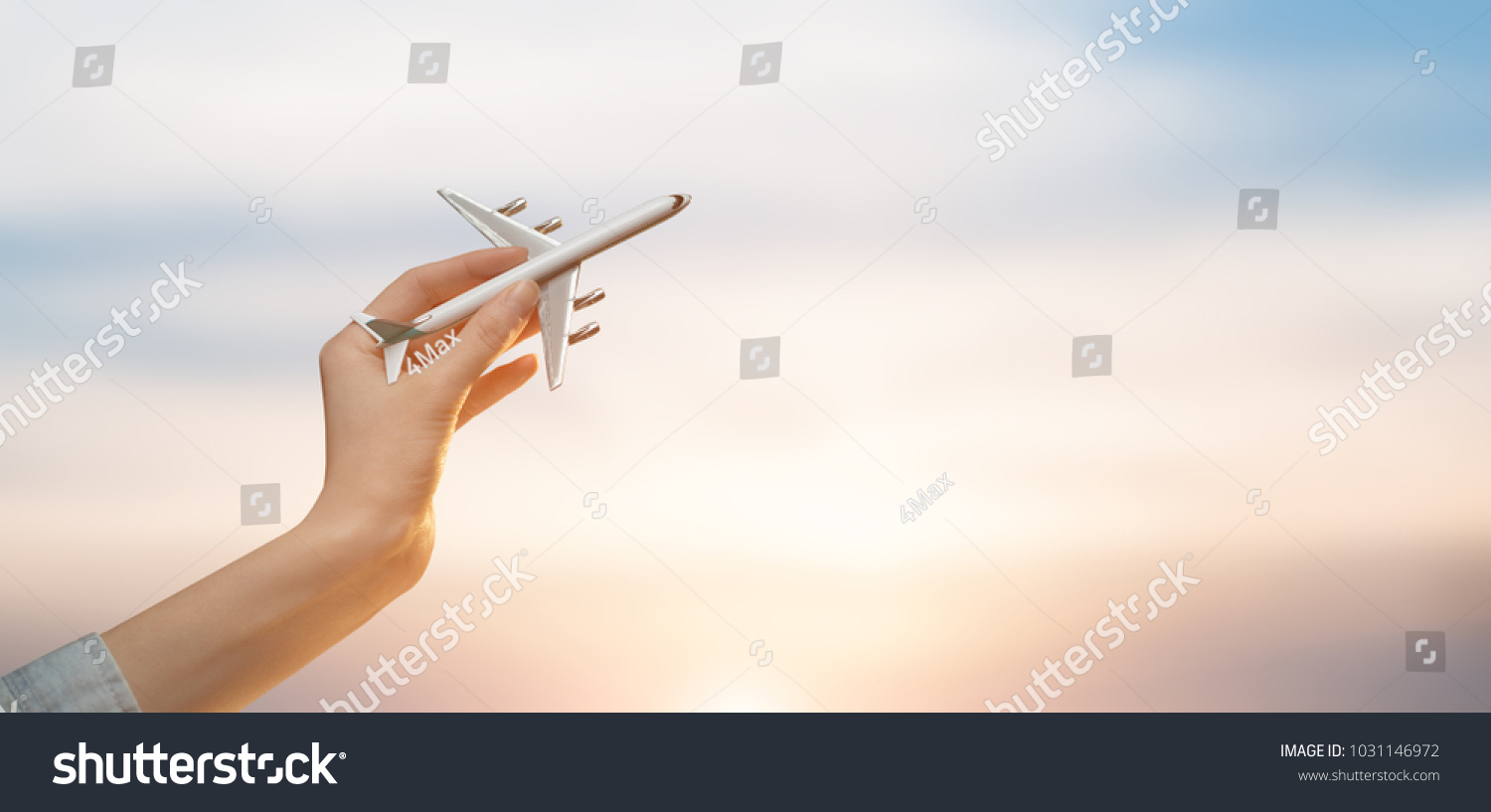 Woman holding airplane in hands and flying over the sunset background