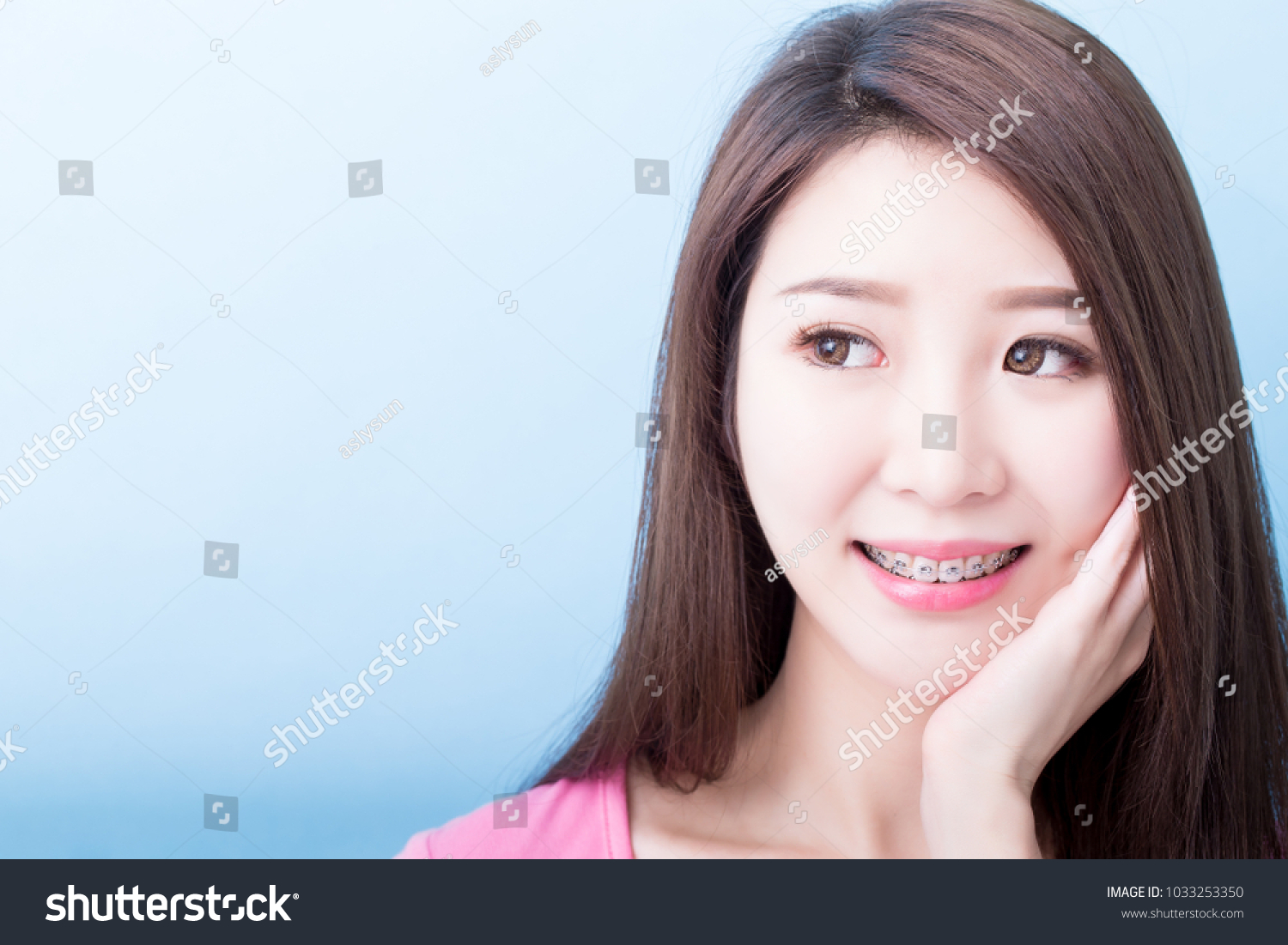 woman wear brace look somewhere and smile happily on the blue background