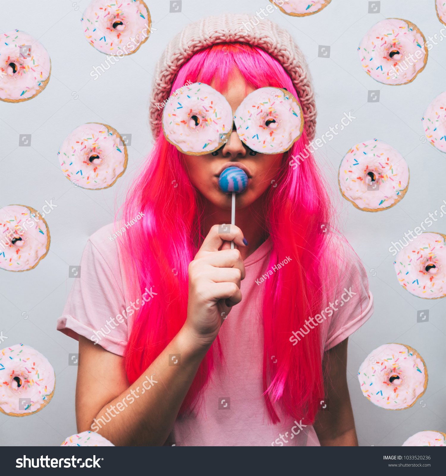 alien girl with donuts for eyes and the beanie hat is sucking candy