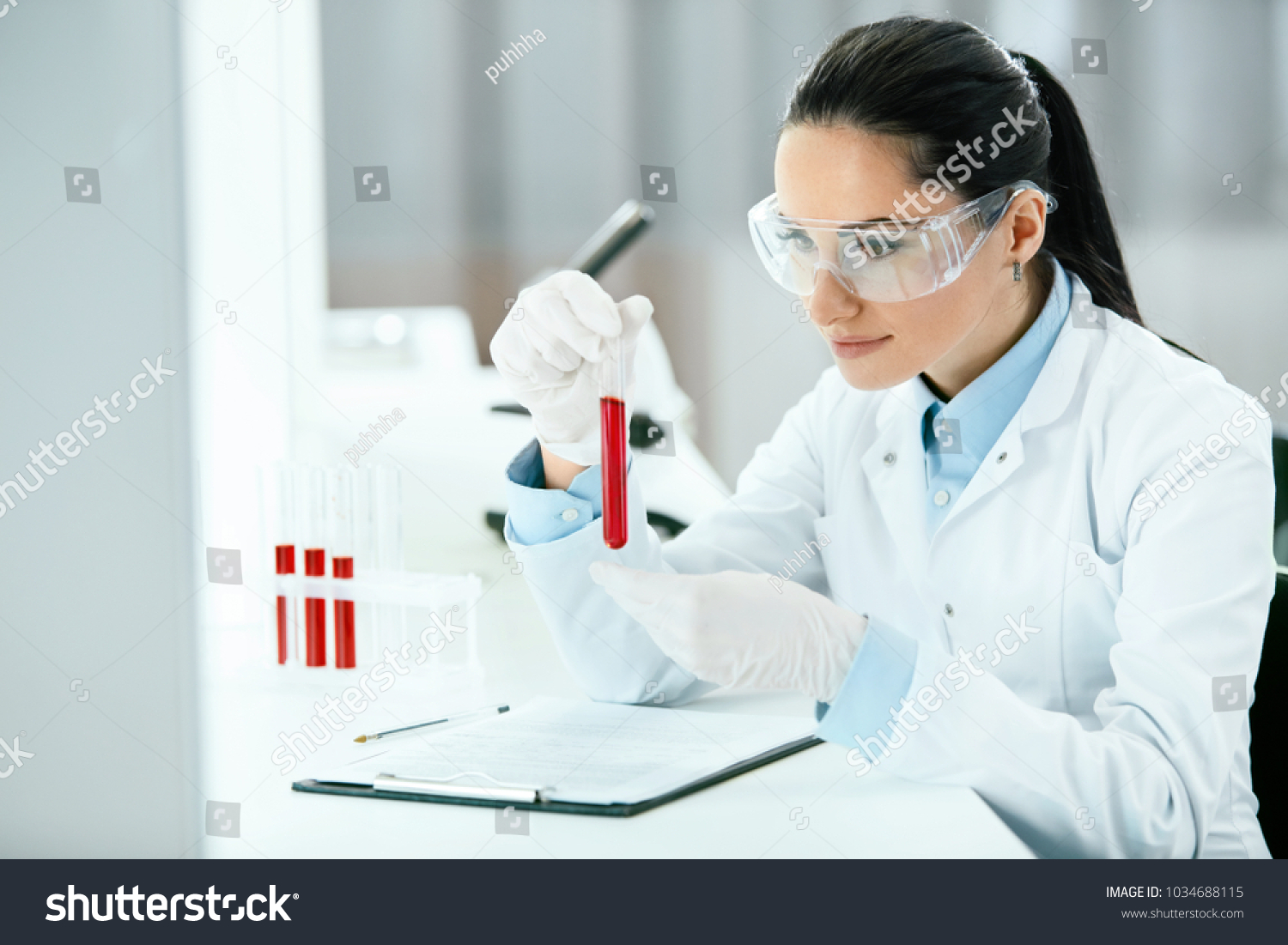 Laboratory. Woman Doing Medical Research With Blood. Portrait Of Beautiful Young Female In White Coat Sitting At Workplace And Working With Blood Sample In Lab. Medical Laboratory. High Resolution