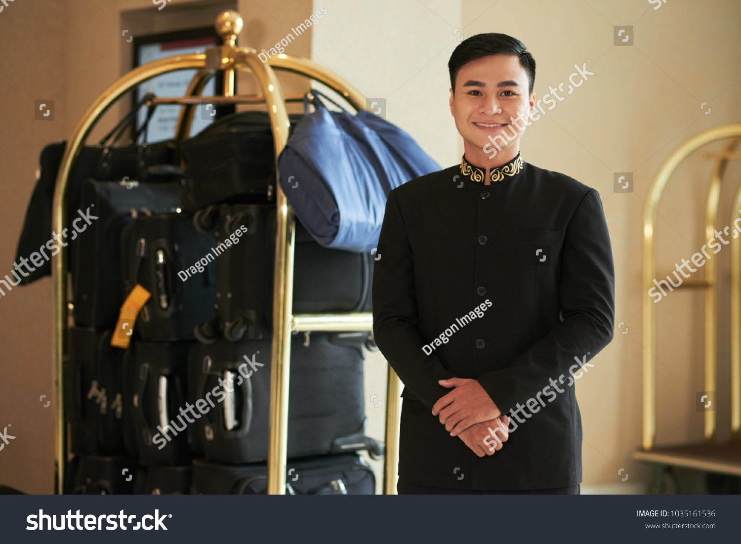 Cheerful Vietnamese porter and hotel baggage cart in the background