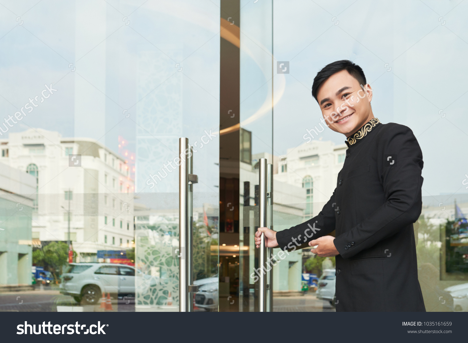 Cheerful Vietnamese hospitable server opening hotel door