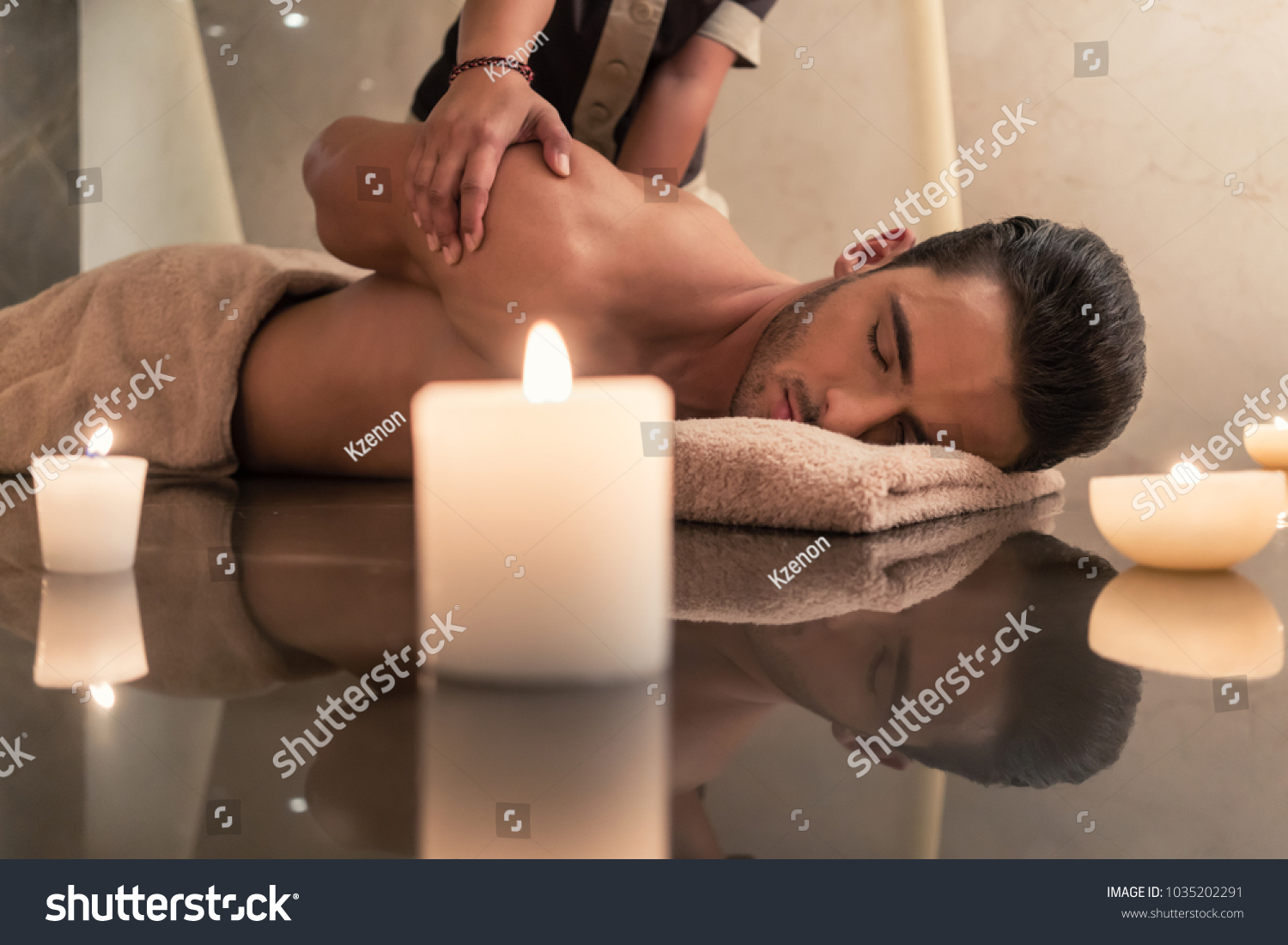 Young muscular man enjoying the healing benefits of traditional Thai massage at luxury spa and wellness center