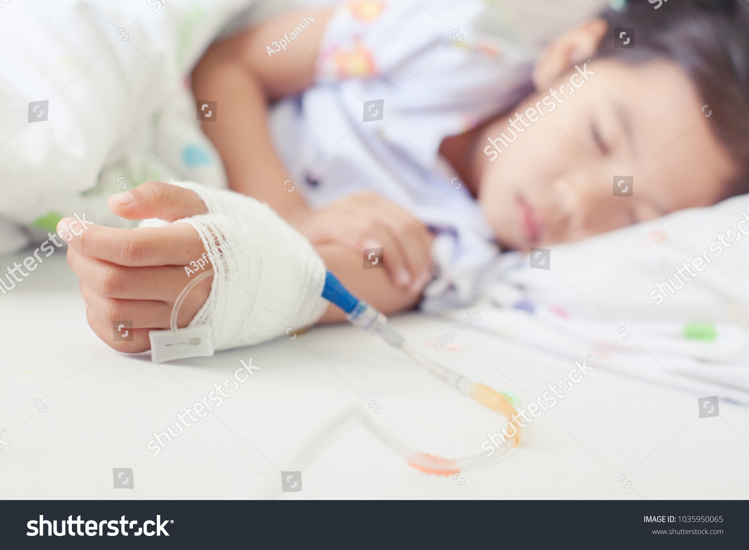 Sick asian little child girl hand who have saline intravenous (iv) drip bandage is sleeping on bed in the hospital