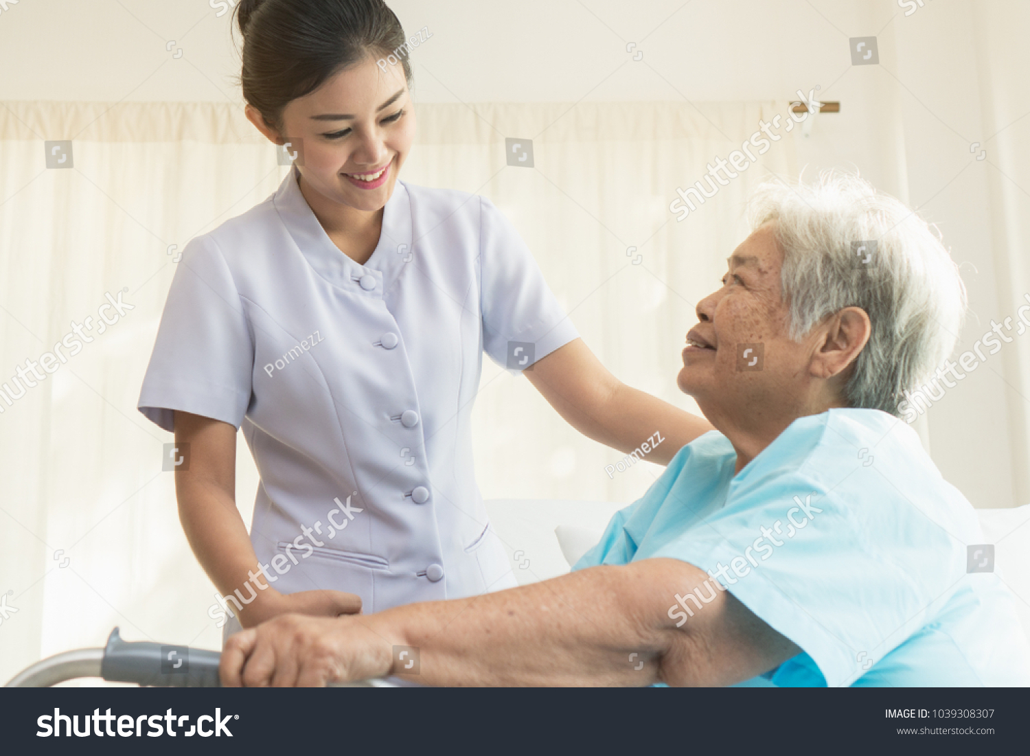Cheerful asian nurse visiting elderly patient to check up after surgery in hospital for giving physical therapy and encouragement.