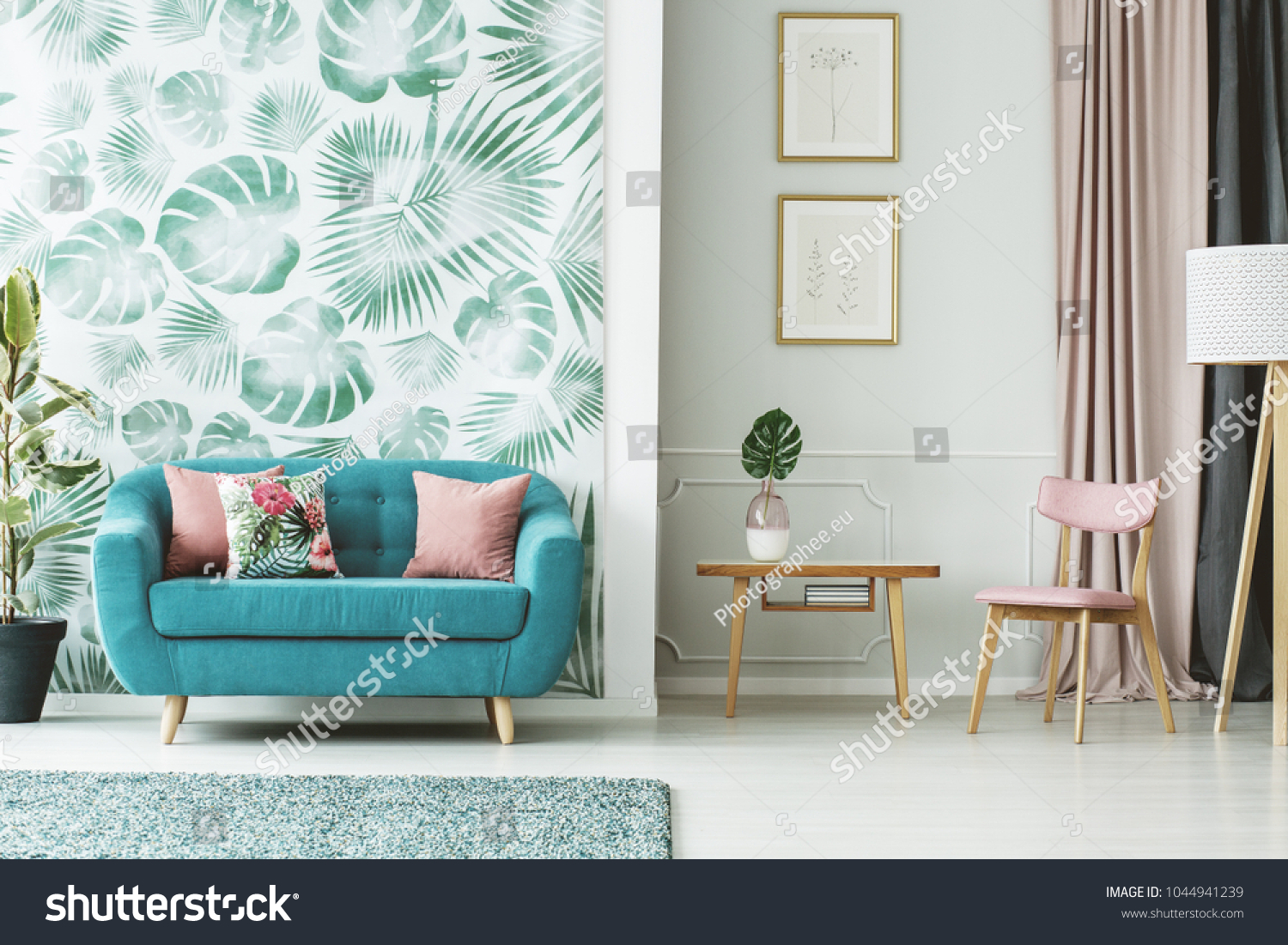 Cozy turquoise couch wooden table and chair in a white and green living room interior with plants and leaf patterns