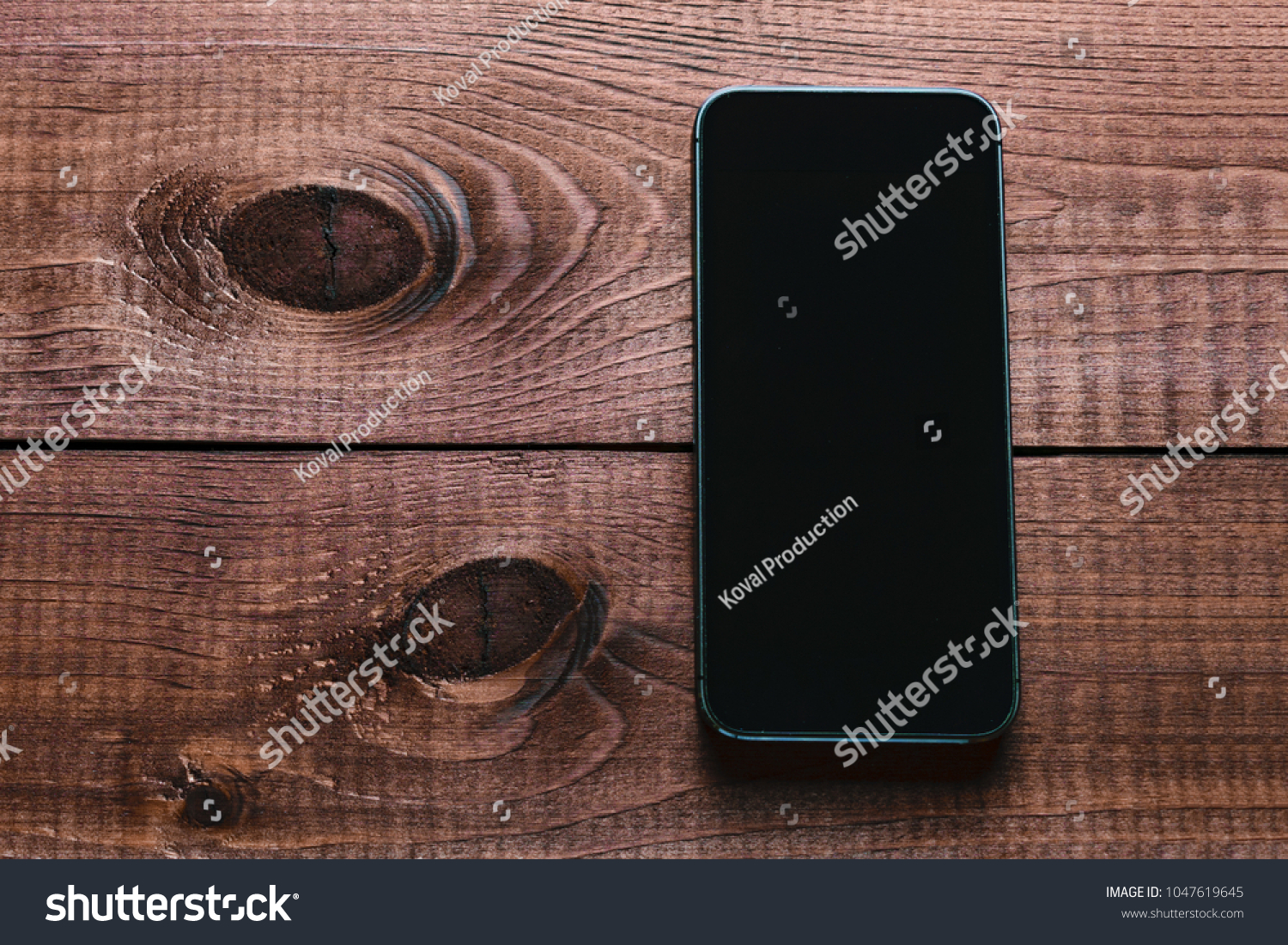 Top view of a modern smartphone with large screen on vintage wooden table. Blank empty display. Mock up