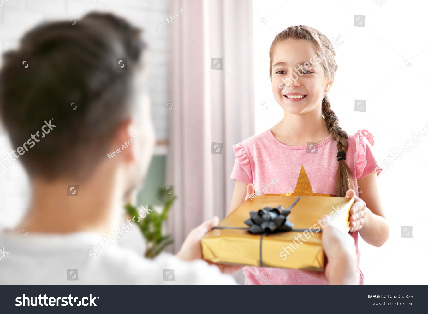 Man receiving gift for Father's Day from his daughter at home