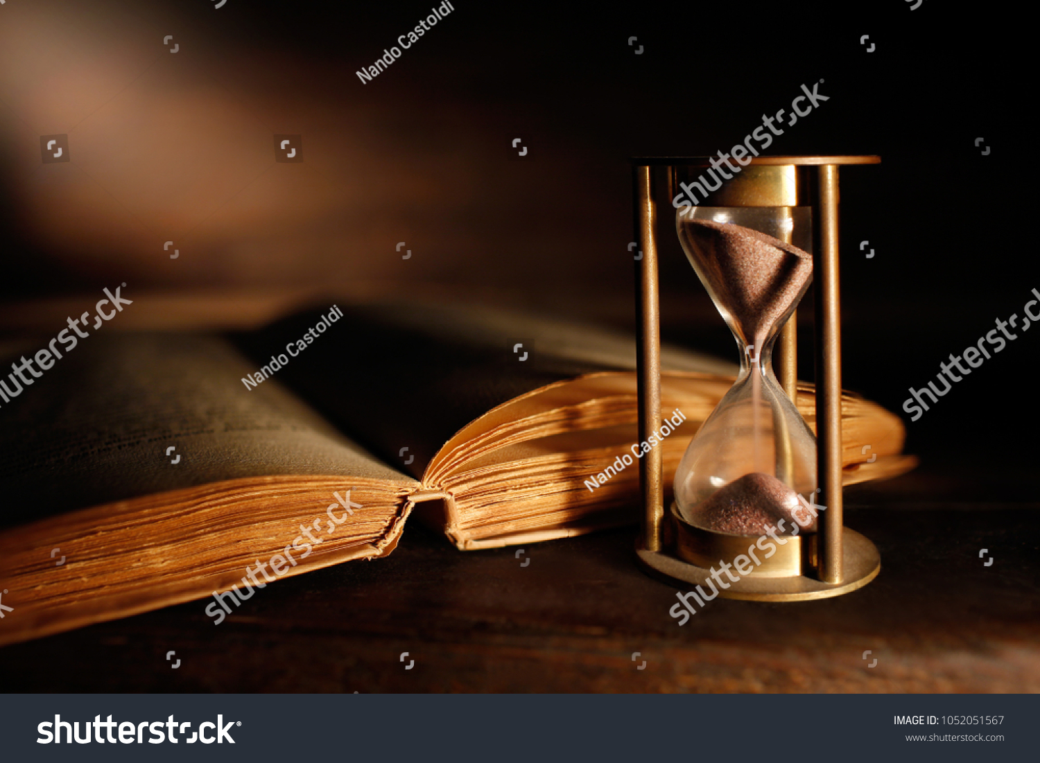old hourglass with open ancient book
