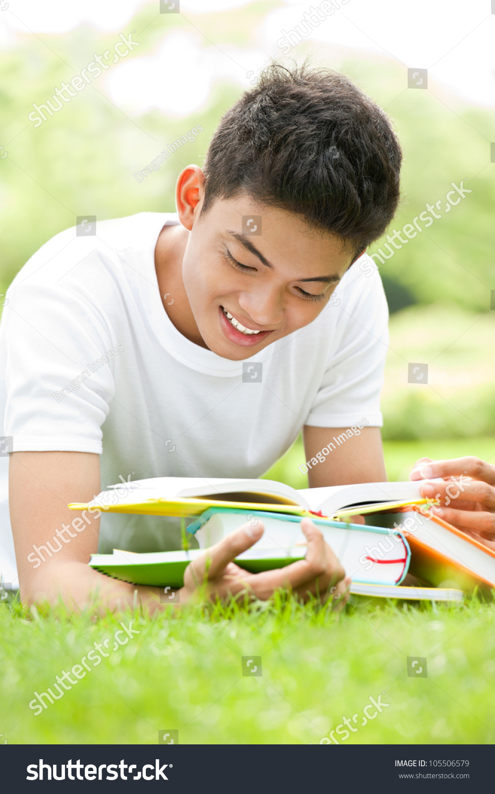 Smiling student studying outdoors with books