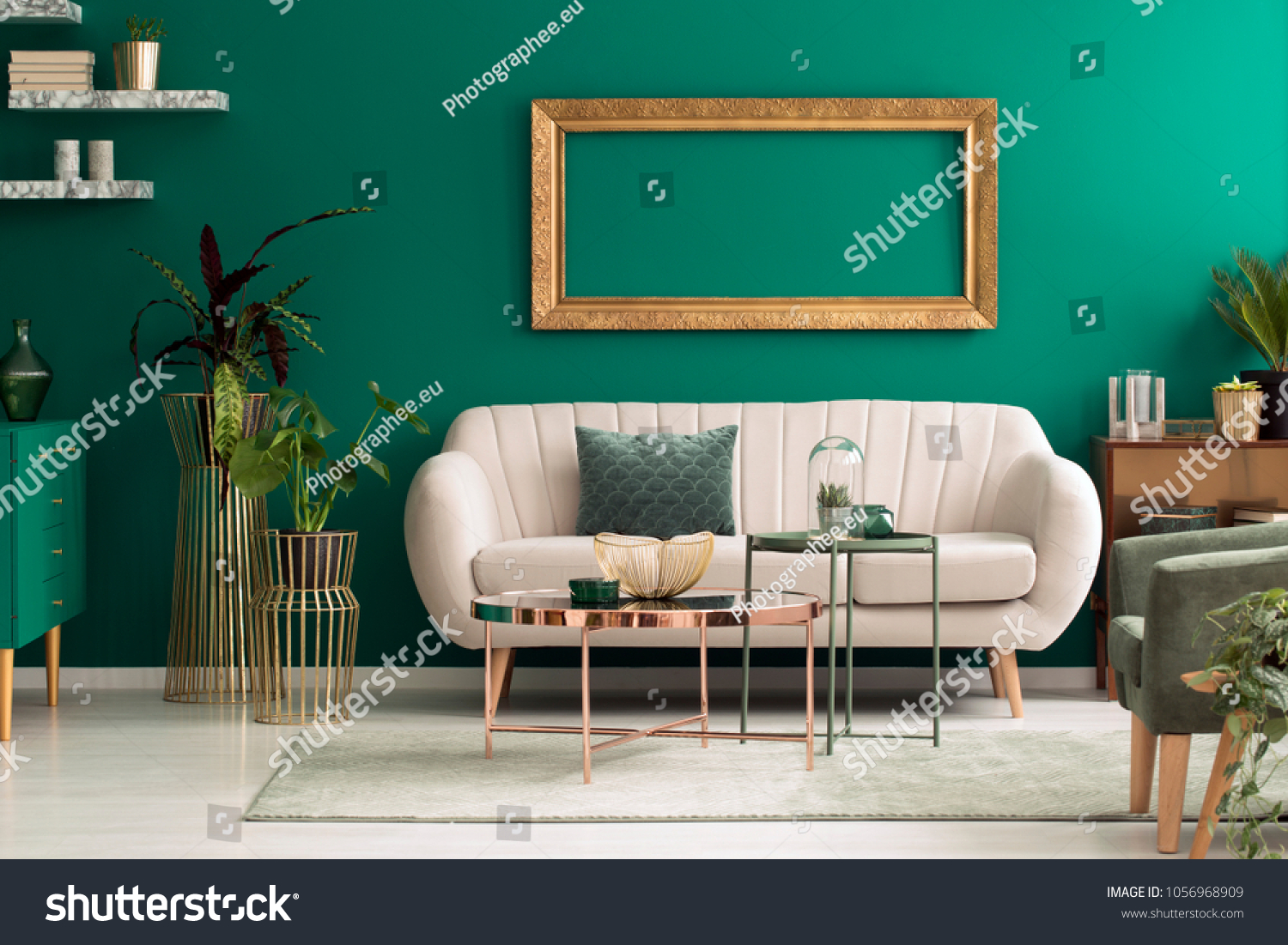 Metal round coffee tables and a beige sofa in a green luxurious living room interior with marble shelves and golden decorations