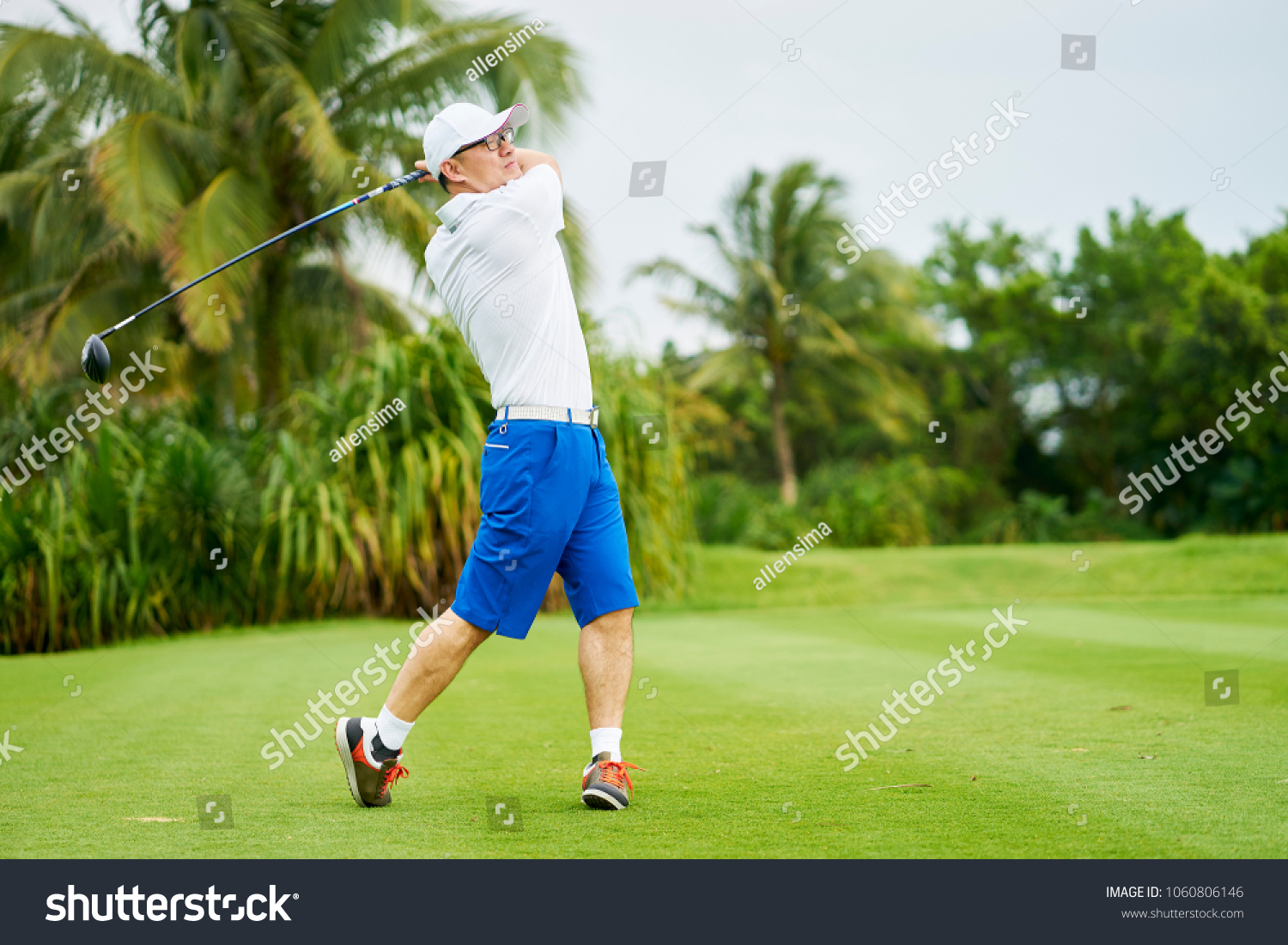 Asian man swinging club in golf course in summer