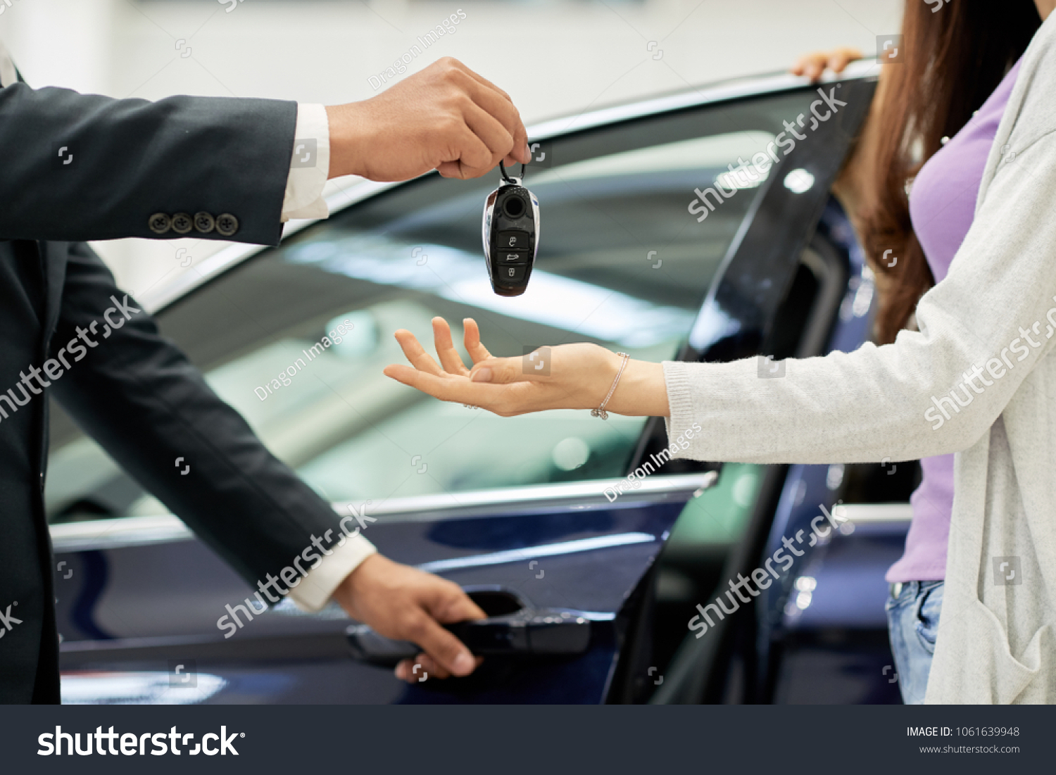 Salesman giving key to female car buyer