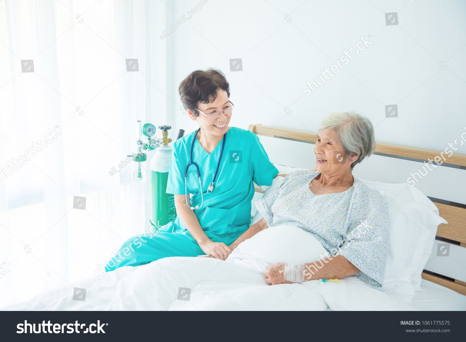 Senior asian female patient smiling with nurse who come to visit her at bed