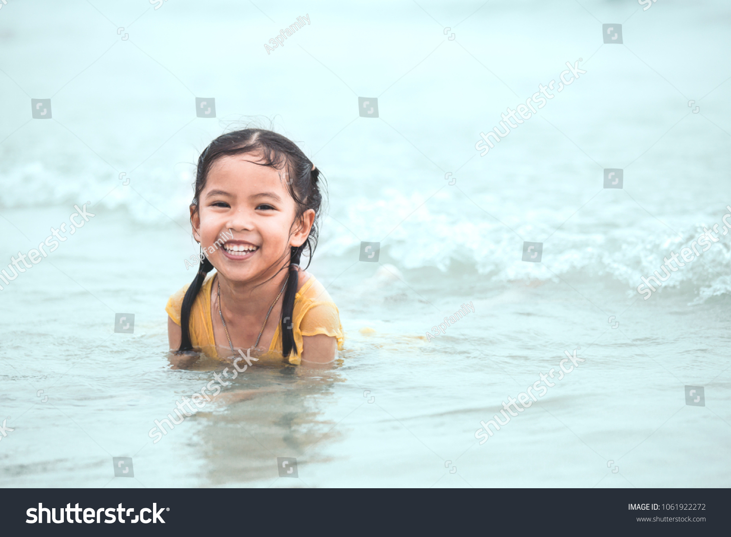 Happy asian little child girl having fun to play water in the sea in summer vacation