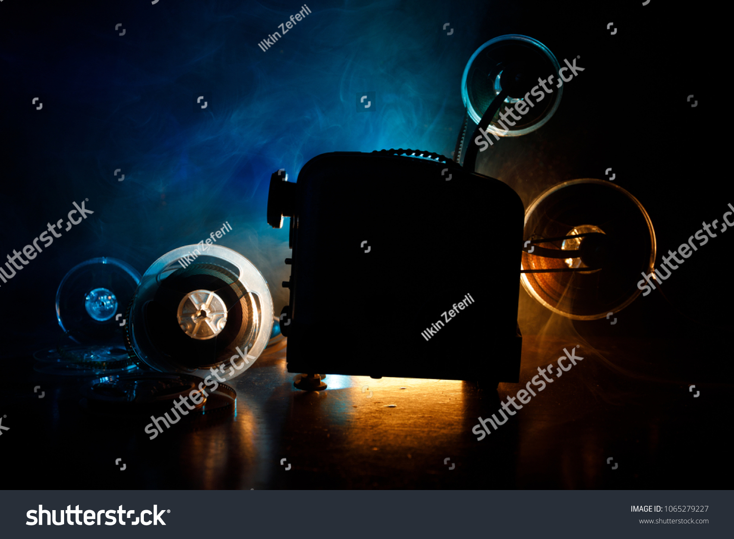 Old style movie projector still-life close-up. Film projector on a wooden background with dramatic lighting and selective focus. Movies and entertainment concept
