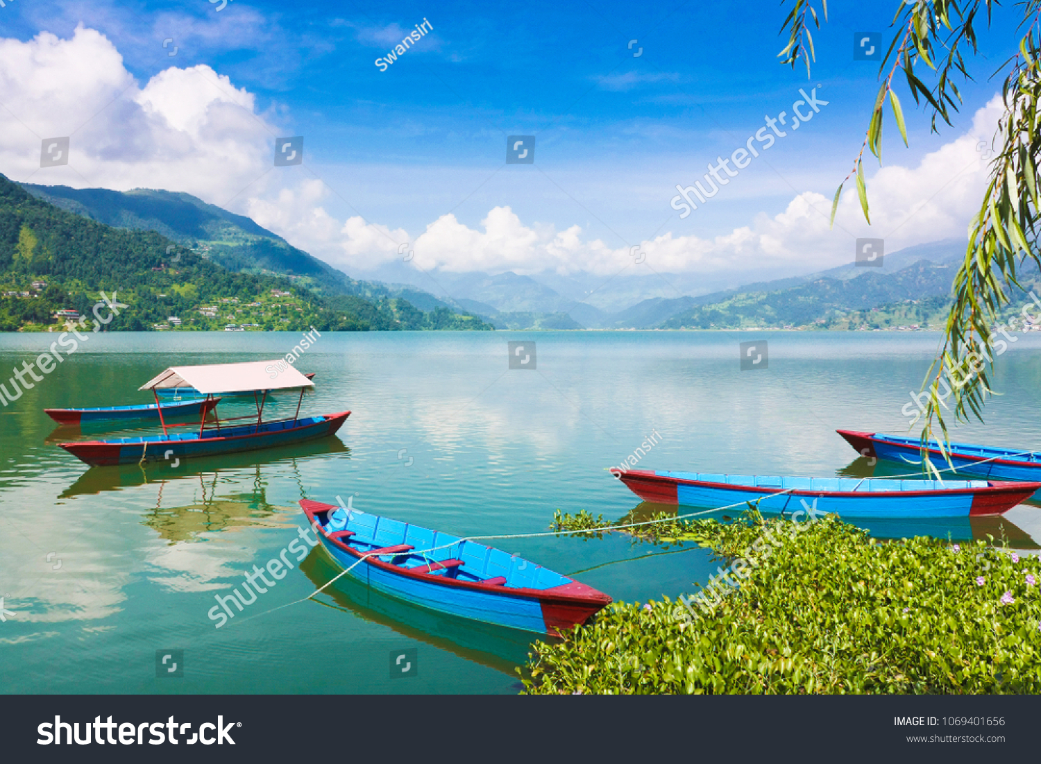 Breathtaking view of Phewa Lake in Pokhara Nepal. Background with colorful boats beautiful blue sky clouds and Himalaya mountains. Traveling Asia Lifestyle vacations holiday concept.
