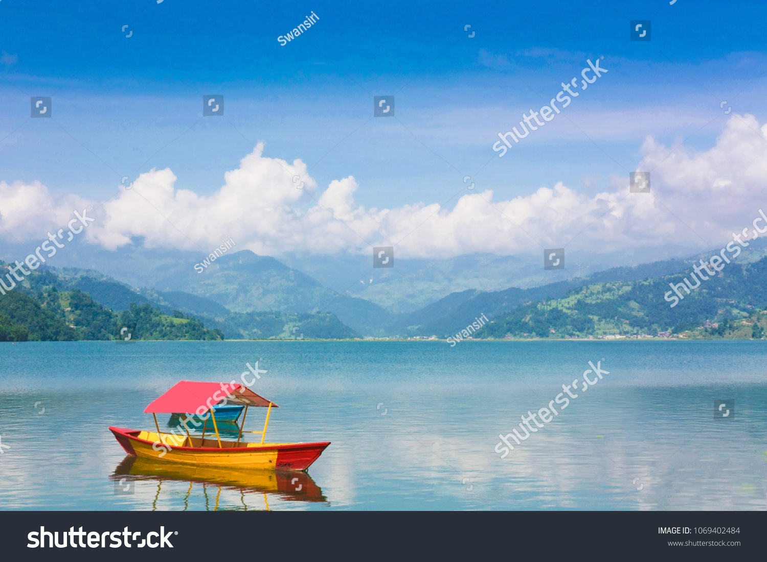 Beautiful landscape of Phewa Lake in Pokhara Nepal. Background with colorful boat beautiful blue sky clouds and Himalaya mountains. Traveling Asia Lifestyle vacations travel concept.