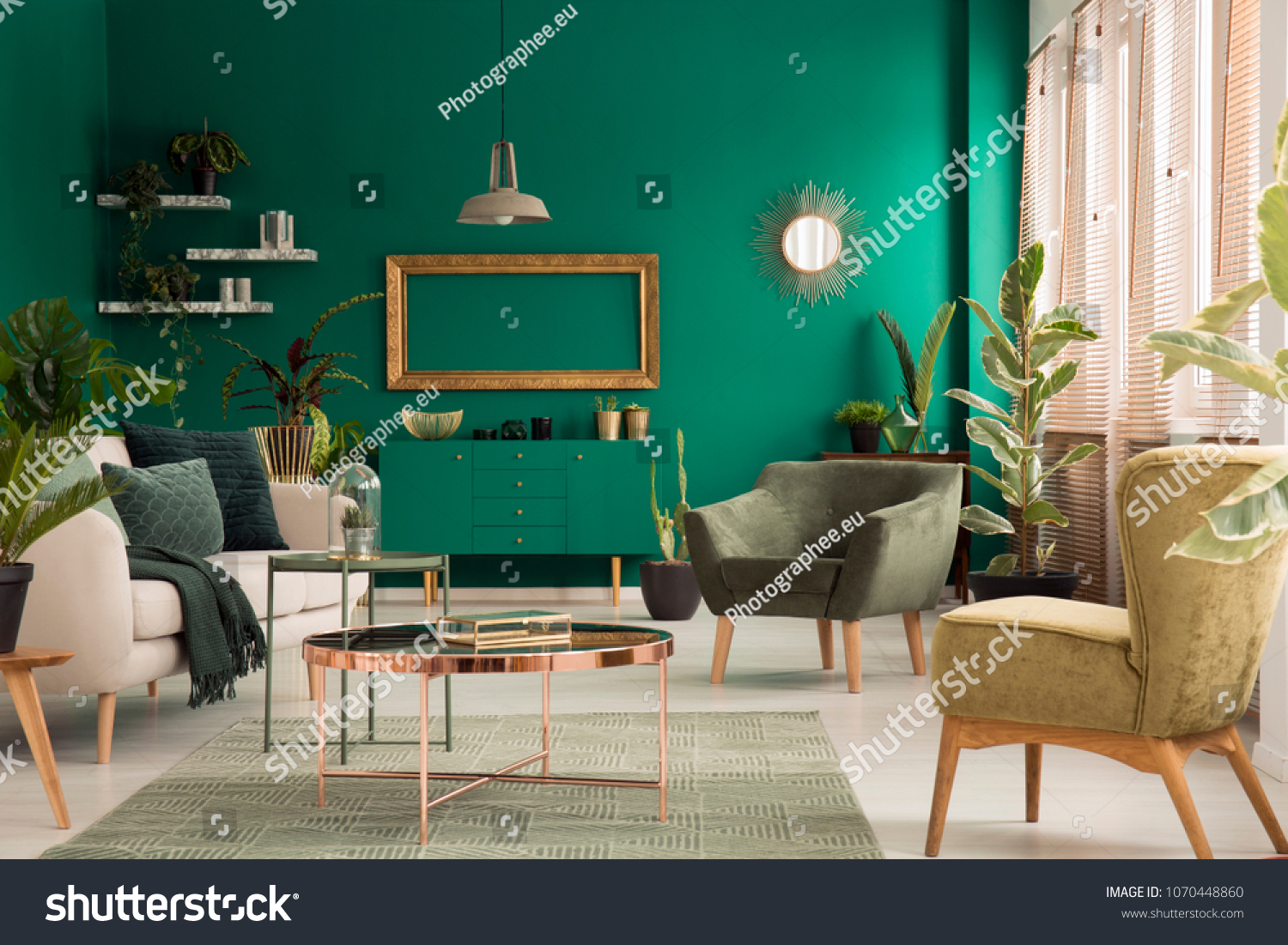 Copper table on rug between beige sofa and armchair in green spacious living room interior with mockup