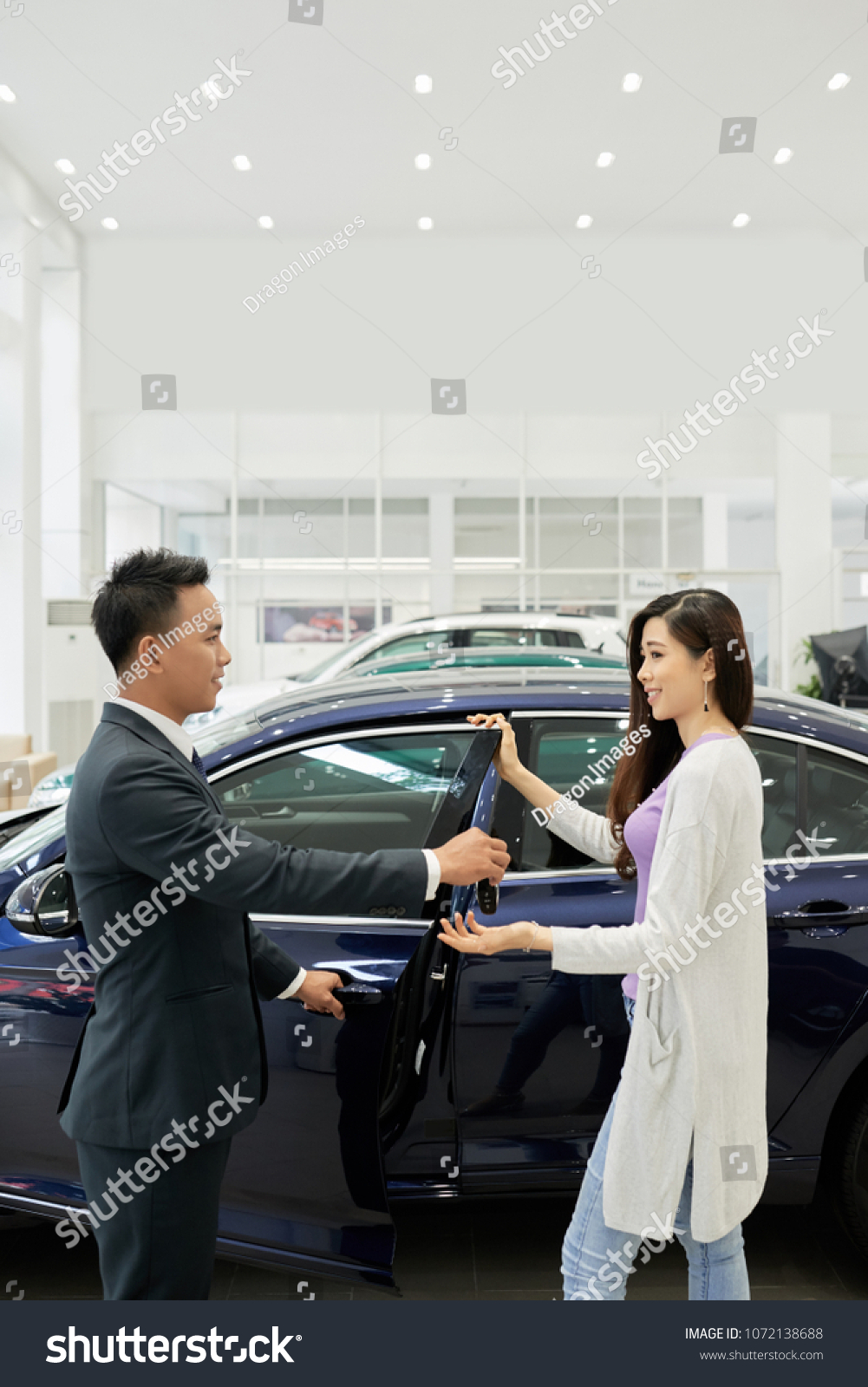Pretty young Vietnamese woman taking keys of her new car