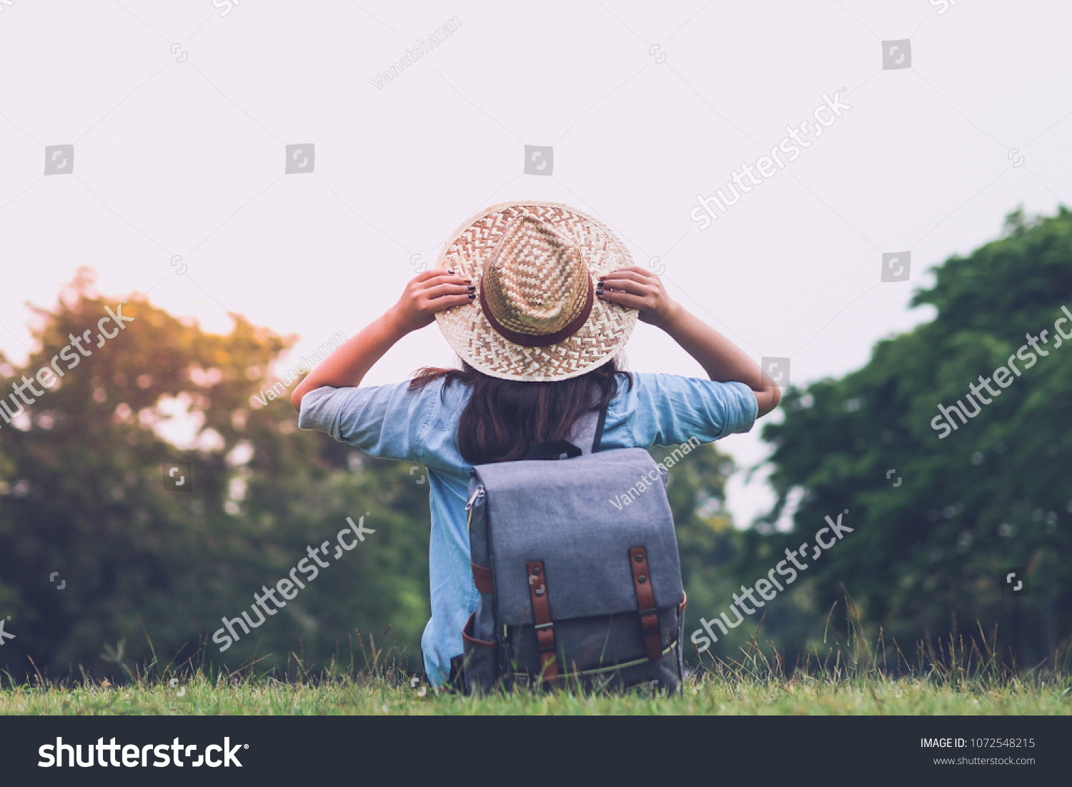 Woman traveler with backpack holding hat and looking at the view in forest travel concept