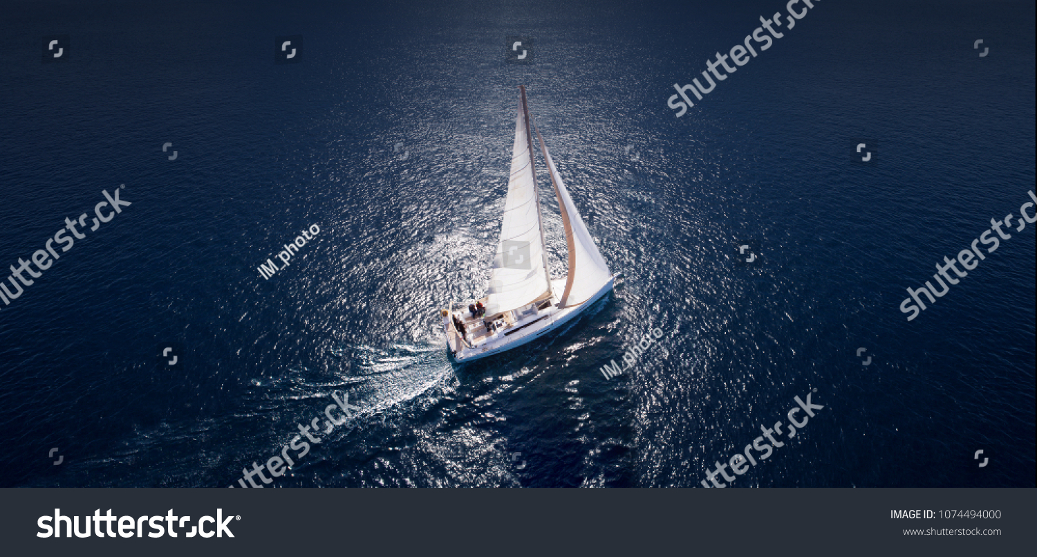 Sailing ship yachts with white sails at opened sea. Aerial - drone view to sailboat in windy condition.