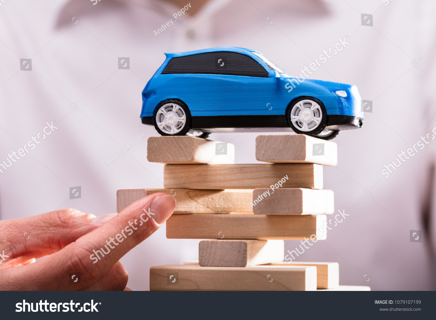 Blue Car Over Businessperson's Finger Arranging Wooden Blocks. 