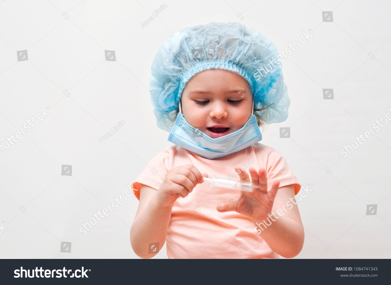 Adorable little girl playing at the doctor on a white background