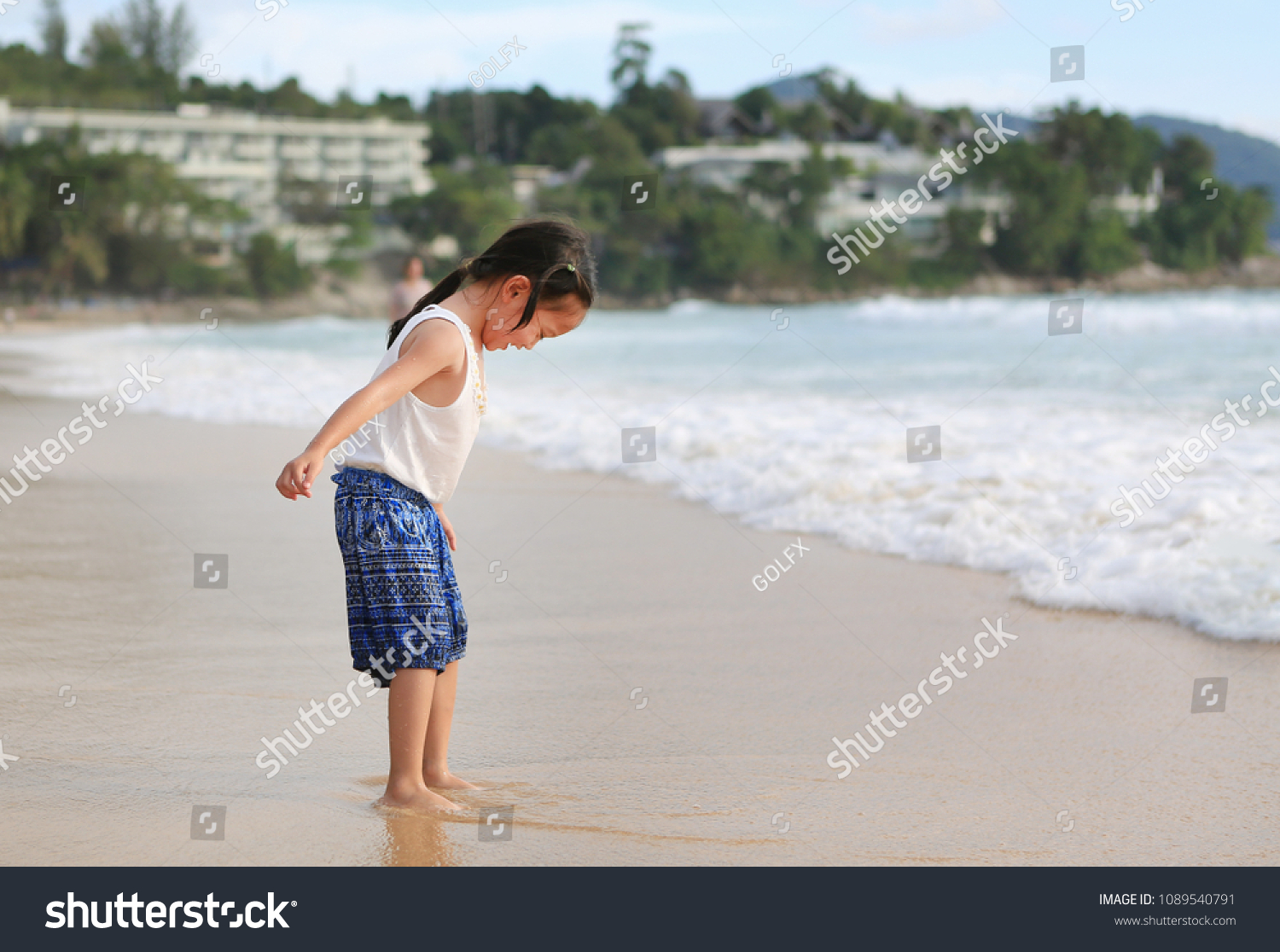 Exciting Asian child girl while come to play sand and sea at the beach on holiday.