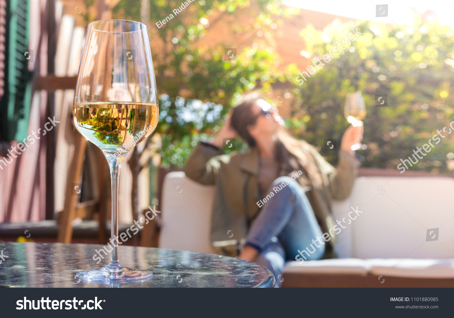 glass of chilled white wine on table over young woman and Tuscany backgound