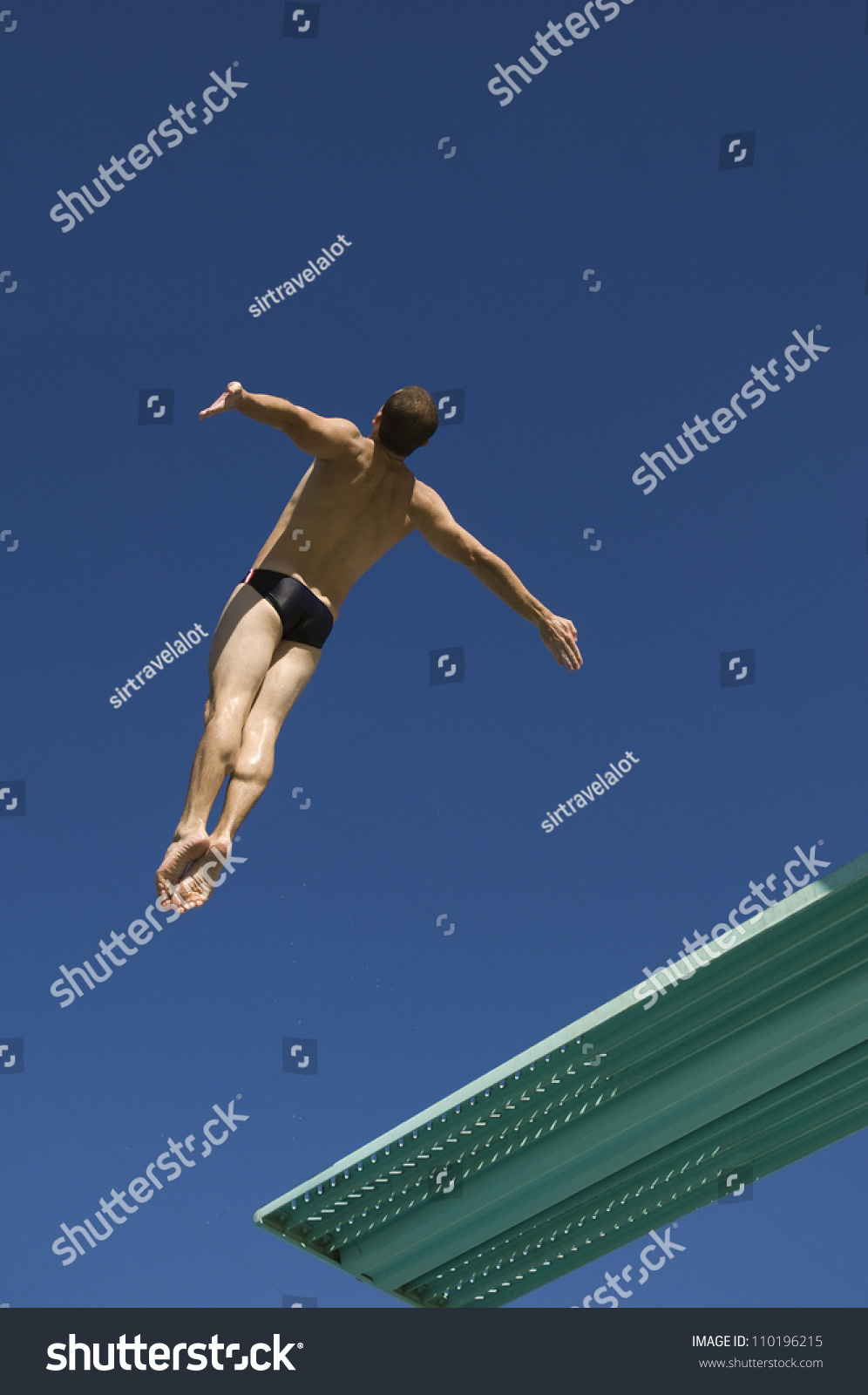 Low angle view of a male diver diving from springboard in midair