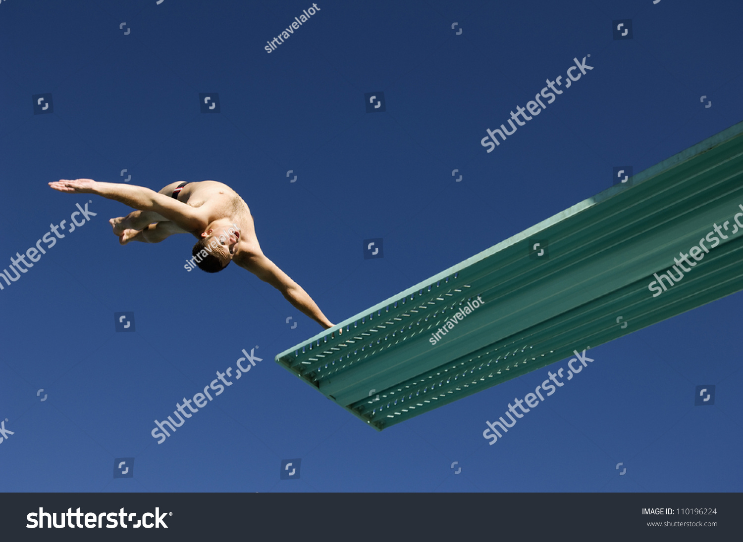 Low angle view of a male diver diving backwards in midair