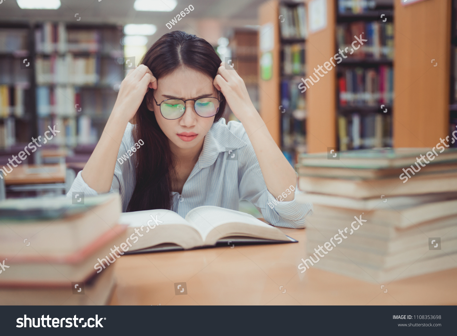 Tired young woman removing eyeglasses massaging eyes after reading book