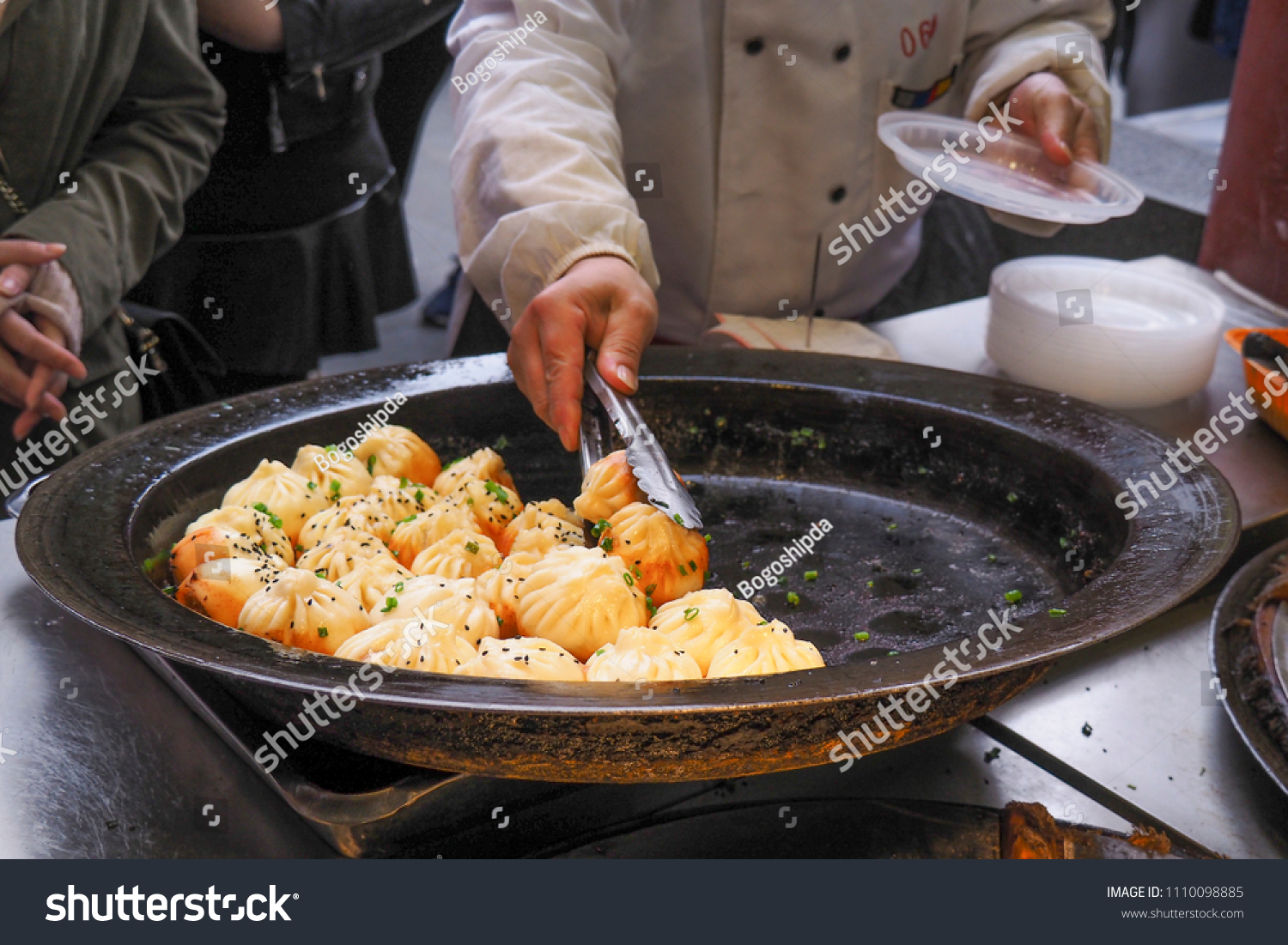 big frying pan with sheng jian bao-traditional chinese pan fried dumplings with minced pork shrimp and vegetables in Shanghai China Cantonese food pan-fried
