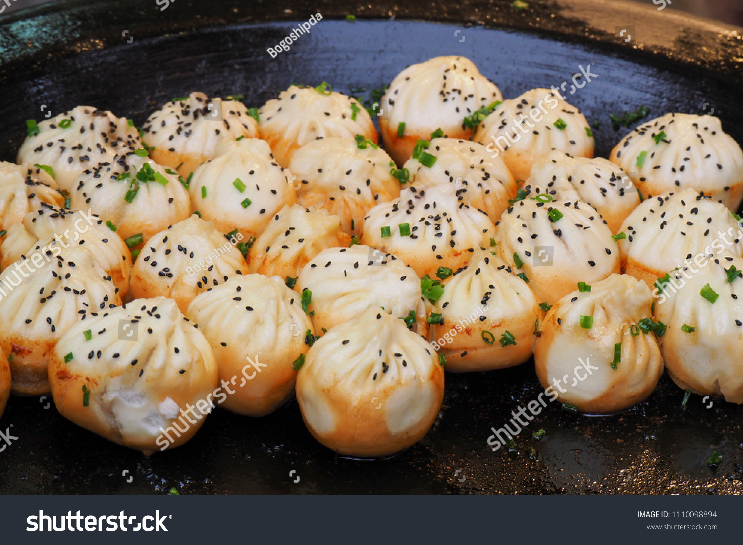 big frying pan with sheng jian bao-traditional chinese pan fried dumplings with minced pork shrimp and vegetables in Shanghai China Cantonese food pan-fried