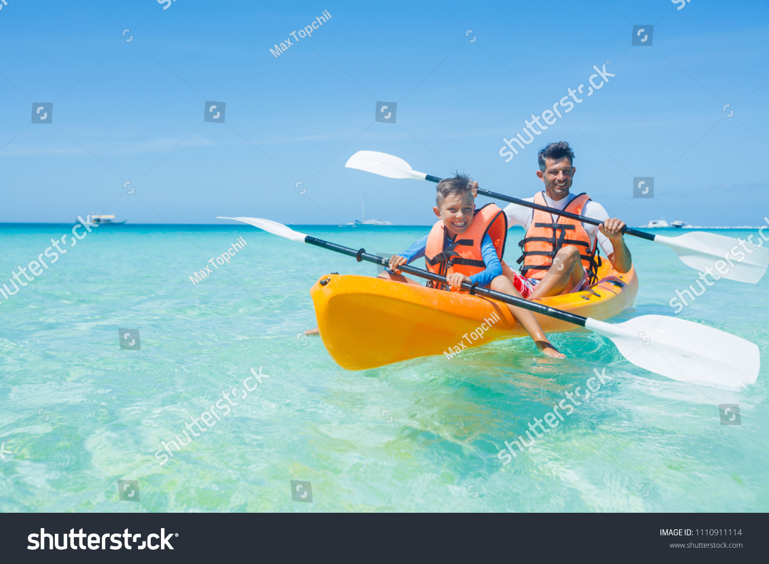 Happy cute boy and his father kayaking at tropical sea on yellow kayak
