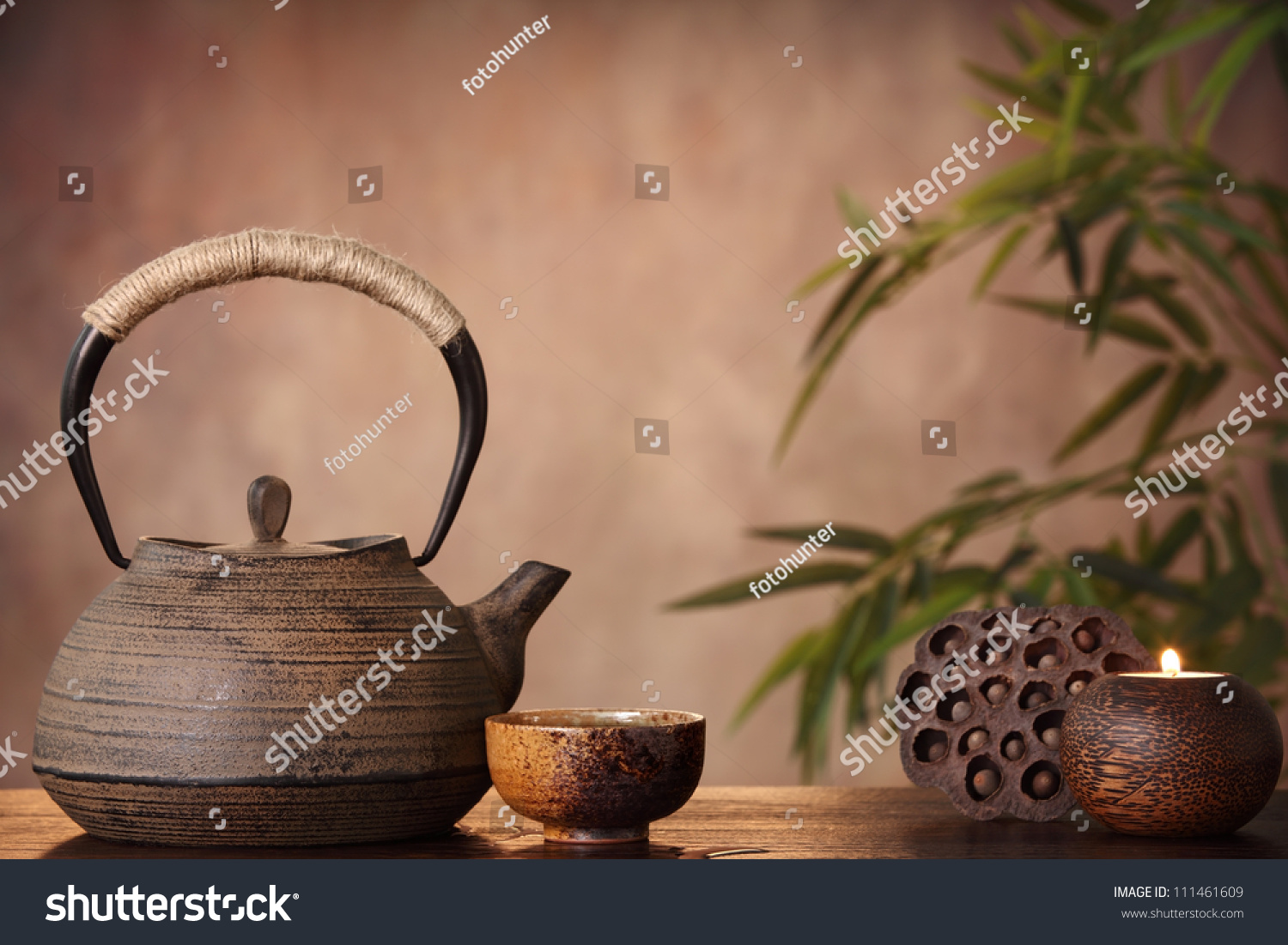 Black iron asian teapot and burning candle vintage style.