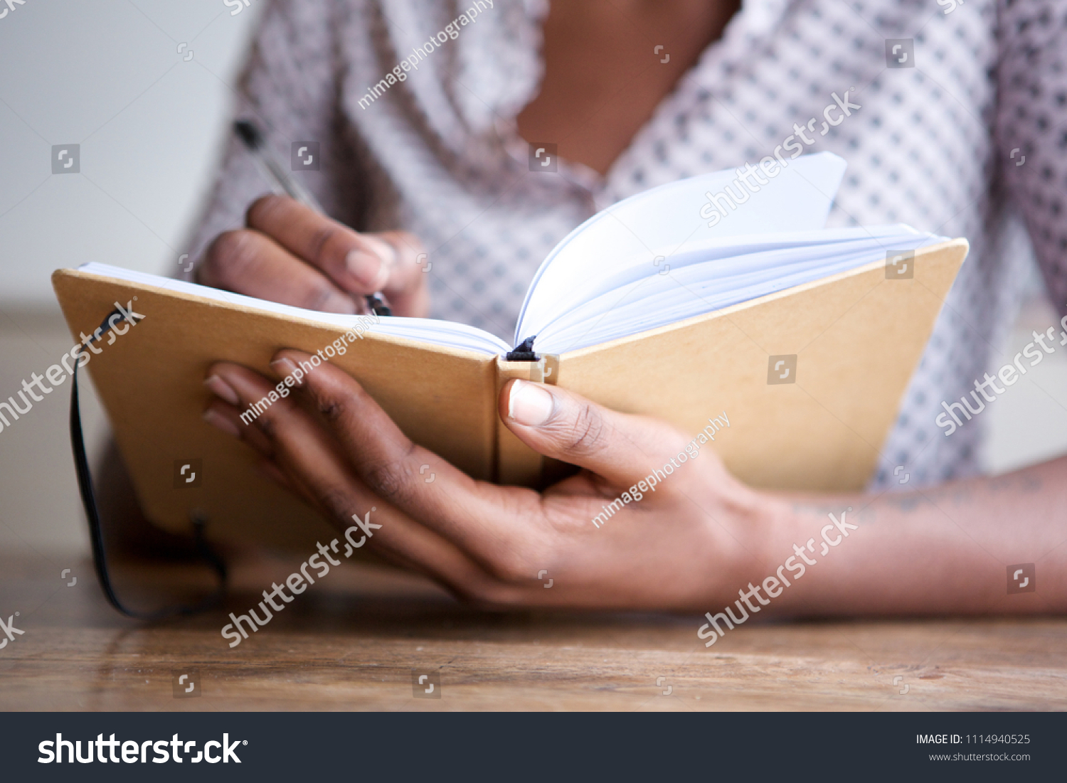 Close up partial portrait of black female author at home writing in journal